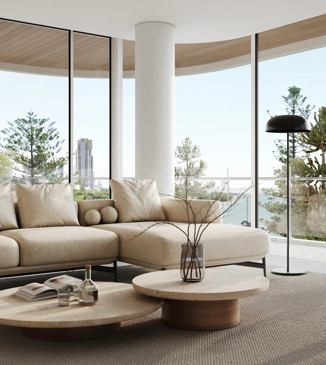 Interior of a stylish living room with large floor-to-ceiling windows offering a stunning ocean view, furnished with a comfortable beige sofa, round coffee tables, and a minimalistic decor.